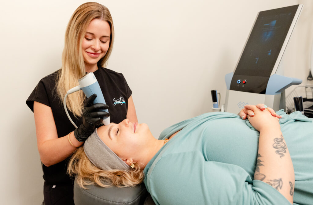 A Smart Skin Med Spa team member administering an Exion Face treatment on a woman's forehead as she lies down in a treatment room at a skin and wellness center in Homewood.