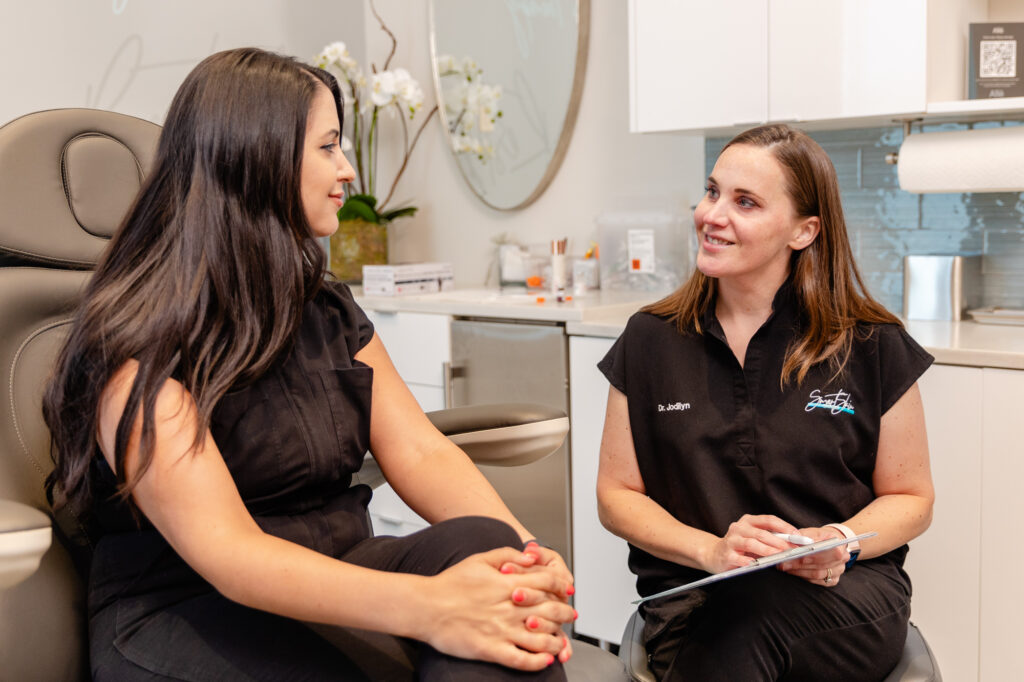 A woman who searched online for a "med spa near me," sitting in a treatment room at Smart Skin Med Spa, speaking with a medical provider.