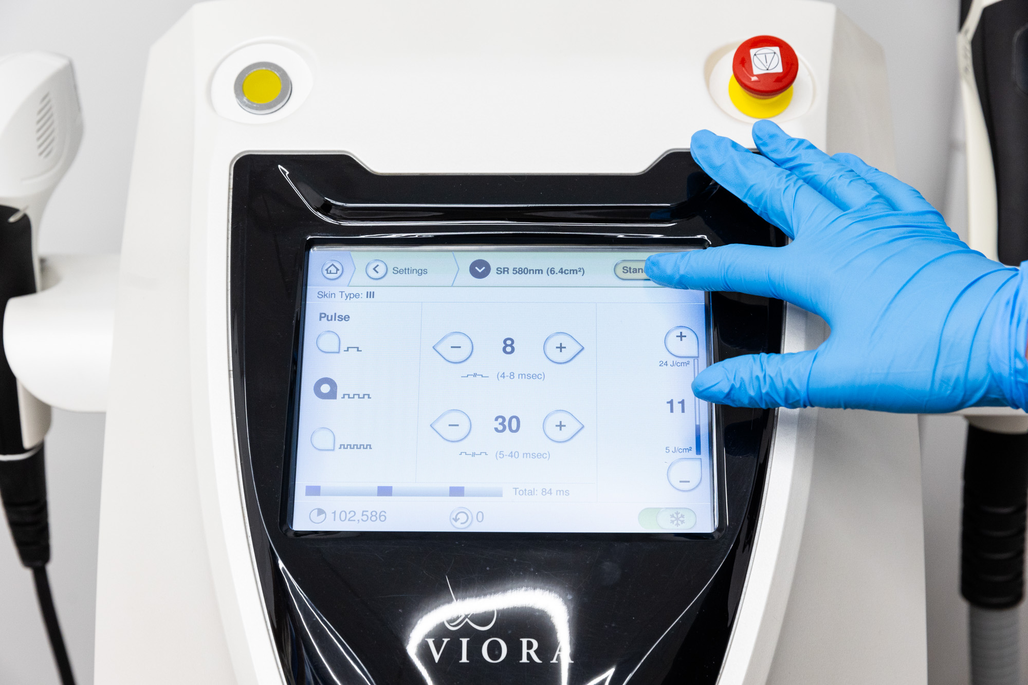 A Smart Skin Med Spa provider wearing blue gloves adjusts Viora's pulse duration and intensity before laser hair removal near Hoover.